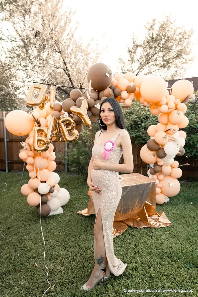 Mom-to-be posing in front of an “Oh Baby” balloon arch at a garden baby shower—collect every guest's photos in one shared album.